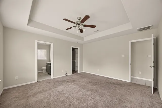 a view of a livingroom with a ceiling fan & windows