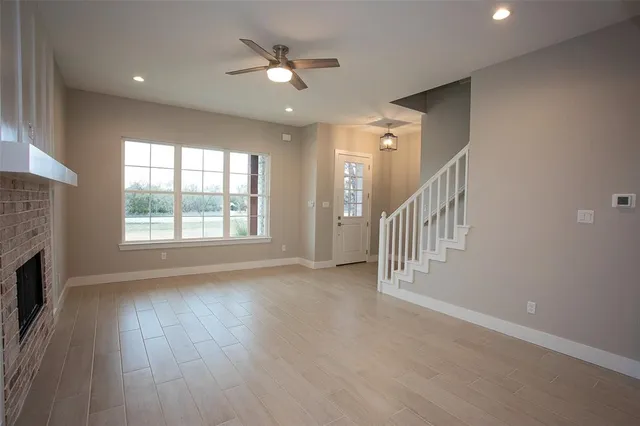 an empty room with wooden floor fan and windows