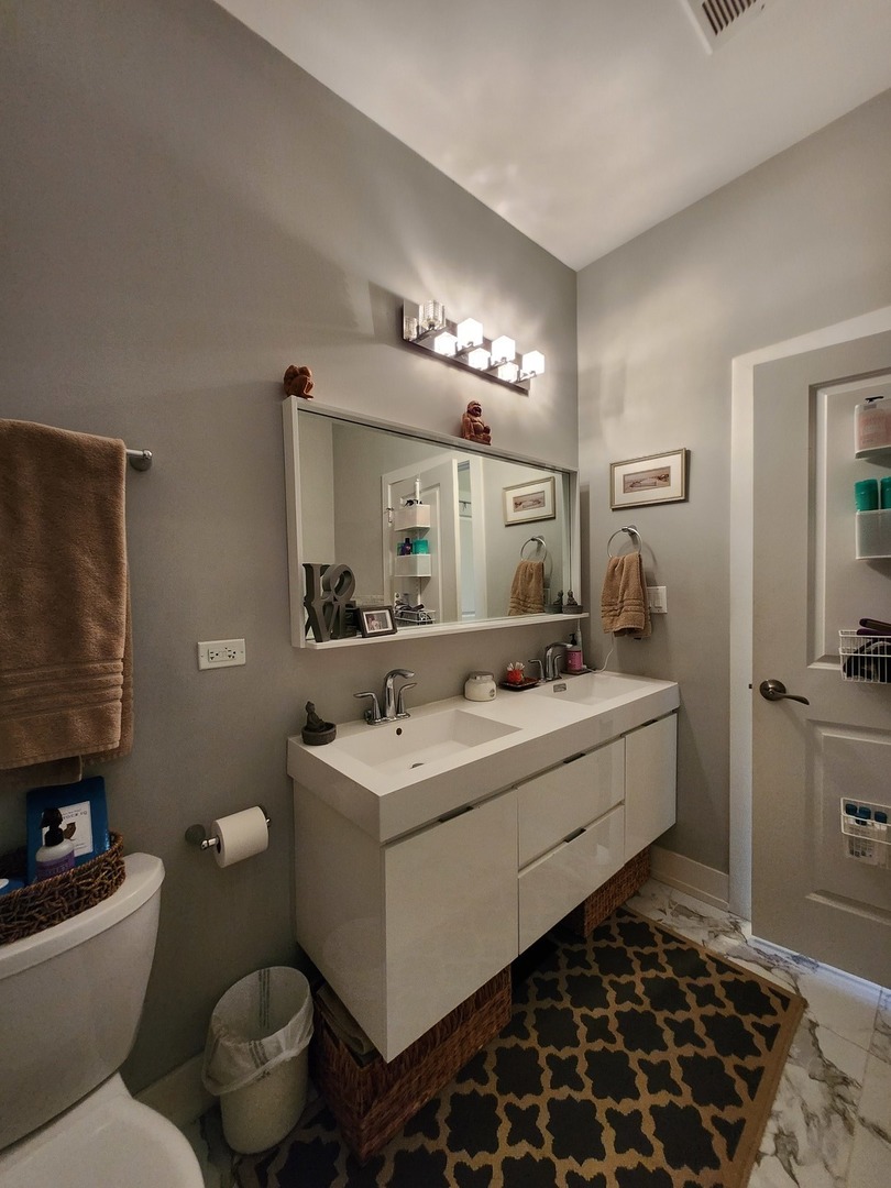 1202 Waukegan Road, Unit 209 Glenview, IL 60025 - Photo 16 of 22 a bathroom with a sink toilet and mirror