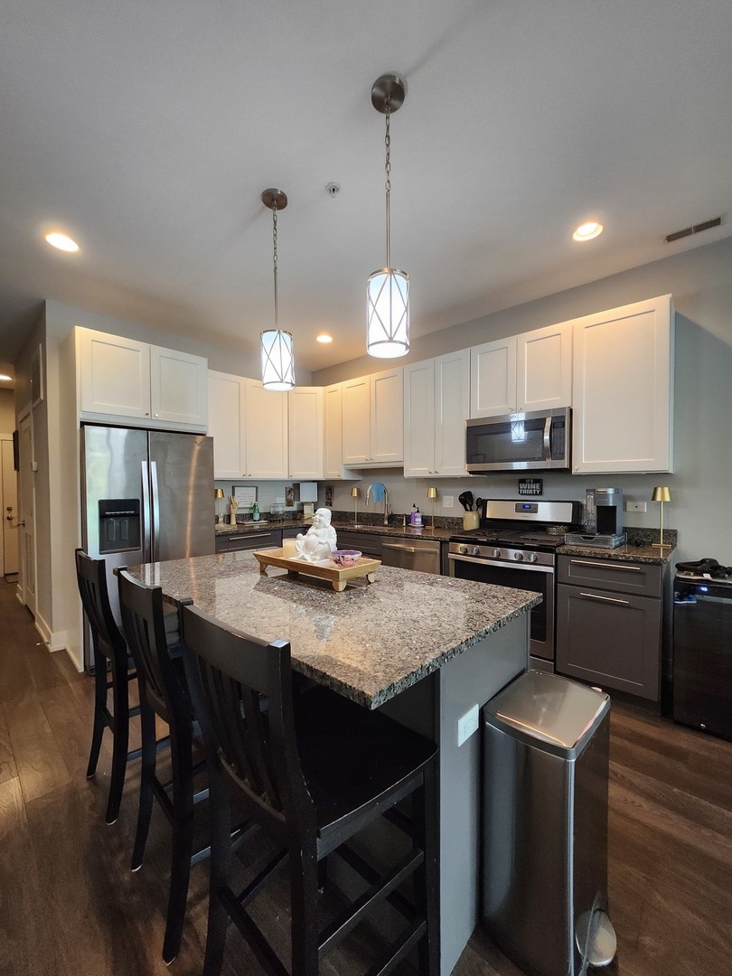 1202 Waukegan Road, Unit 209 Glenview, IL 60025 - Photo 3 of 22 a kitchen with kitchen island granite countertop a sink counter and chairs