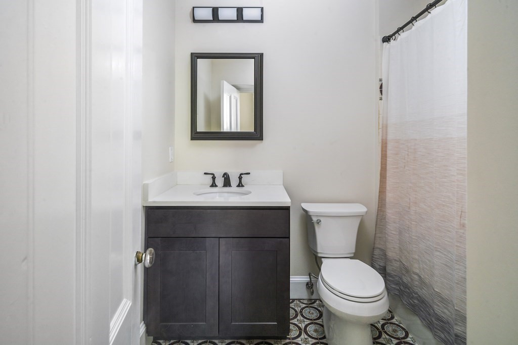 1000 Centre Street, Unit 3 Boston, MA 02130 - Photo 9 of 14 a bathroom with a toilet sink and mirror
