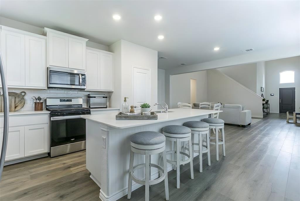 705 Jessica Lynn Lane Anna, TX 75409 - Photo 8 of 26 a kitchen with stainless steel appliances granite countertop a stove a sink a microwave a dining table and chairs