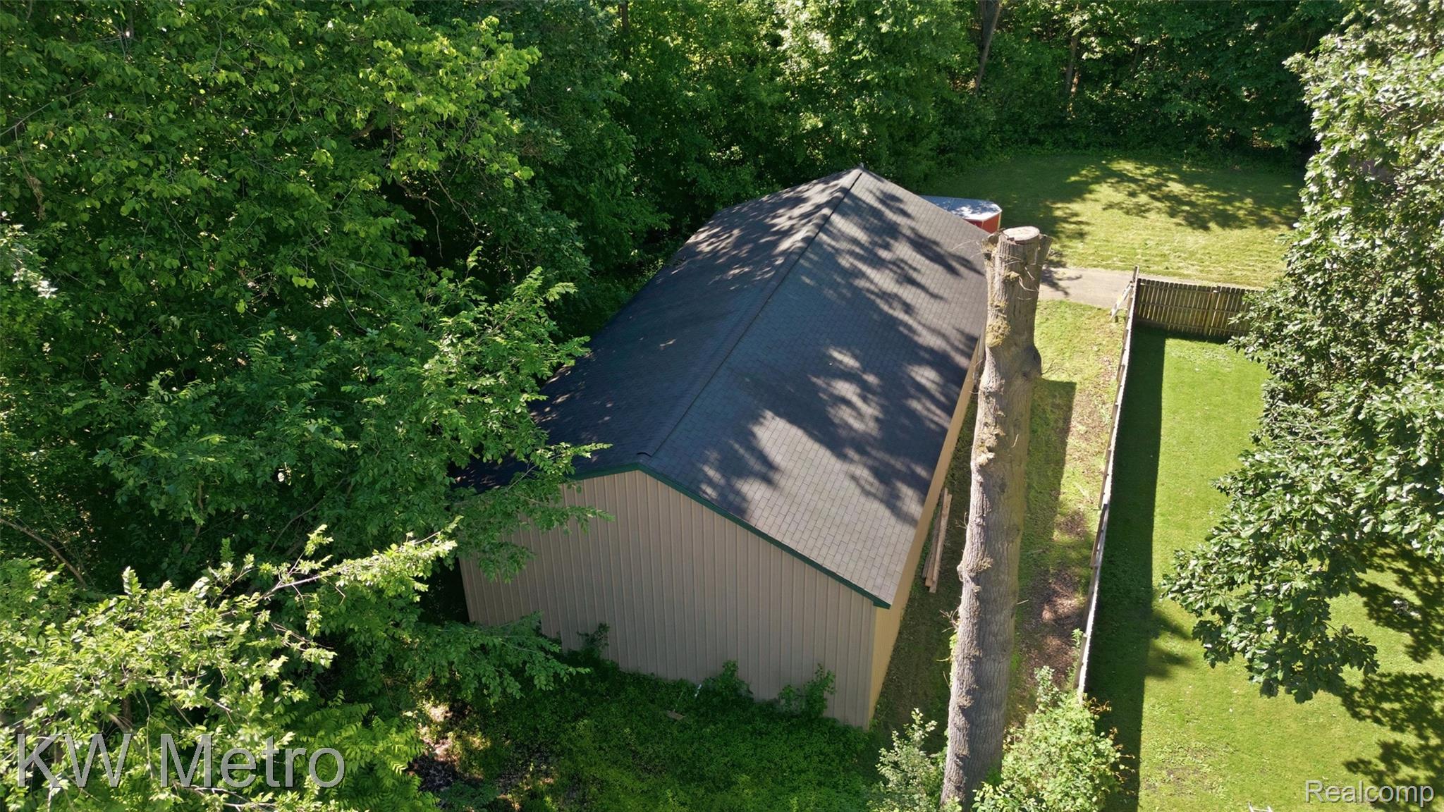 22733 Sumpter Road Belleville, MI 48111 - Photo 45 of 52 Utility building with a dark shingle roof and light-colored siding, bordered by mature trees and a manicured lawn