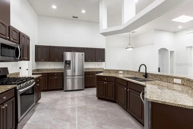 a kitchen with granite countertop a sink stainless steel appliances and cabinets