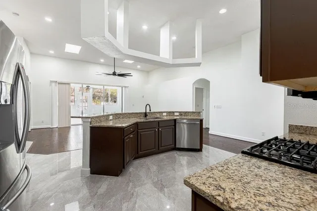 a kitchen with stainless steel appliances granite countertop a stove a sink a refrigerator and a cabinets