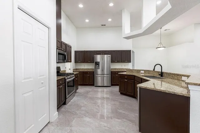 a open kitchen with stainless steel appliances granite countertop a sink stove oven and refrigerator