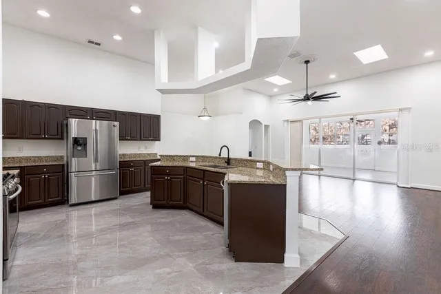 a large kitchen with stainless steel appliances kitchen island granite countertop a large counter top and wooden floors