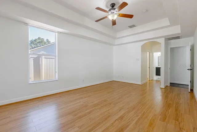 a view of an empty room with window and wooden floor