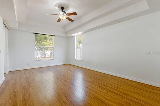 a view of an empty room with a window and wooden floor