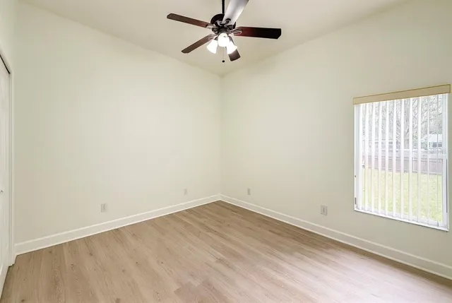 an empty room with a window and a fan
