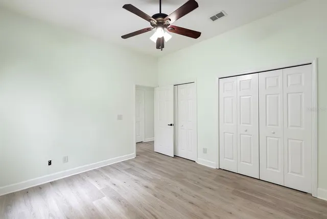an empty room with wooden floor ceiling fan and window