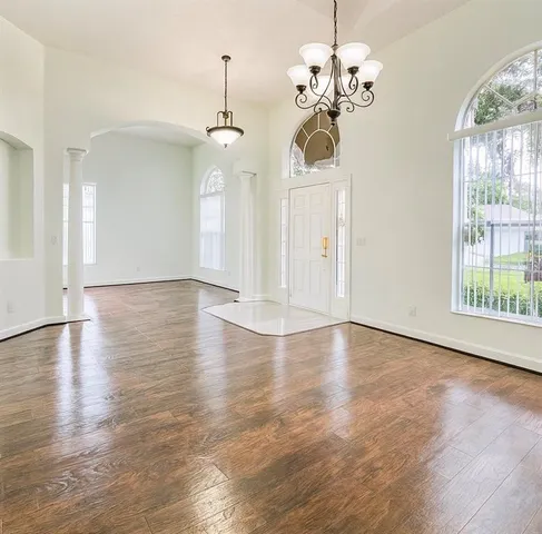 a view of a room with wooden floor chandelier and windows