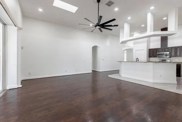 an empty room with wooden floor and a kitchen space
