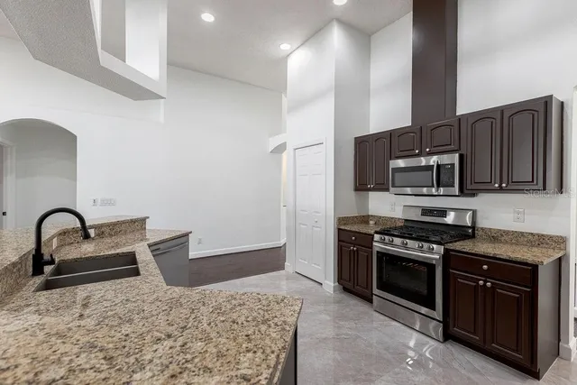 a kitchen with stainless steel appliances granite countertop a stove a sink and a microwave