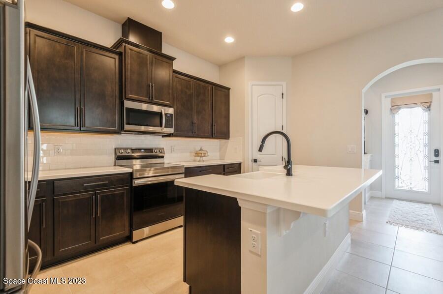 8072 Rungsted Lane Melbourne, FL 32940 - Photo 14 of 59 a kitchen with stainless steel appliances a sink stove and refrigerator