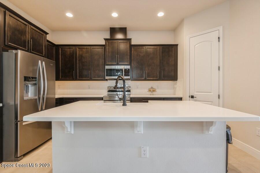 8072 Rungsted Lane Melbourne, FL 32940 - Photo 15 of 59 a kitchen with kitchen island a sink stainless steel appliances and cabinets