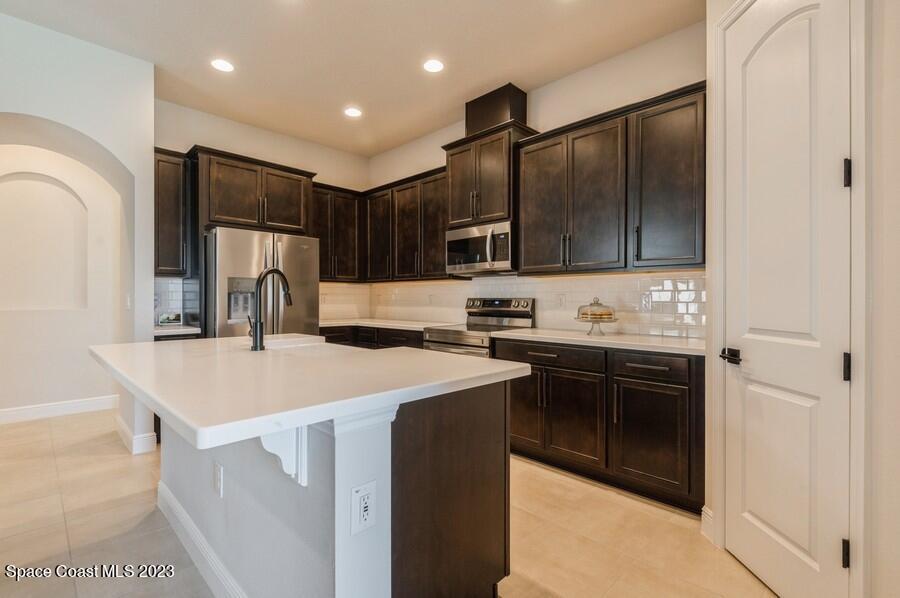 8072 Rungsted Lane Melbourne, FL 32940 - Photo 16 of 59 a kitchen with kitchen island a sink appliances and cabinets