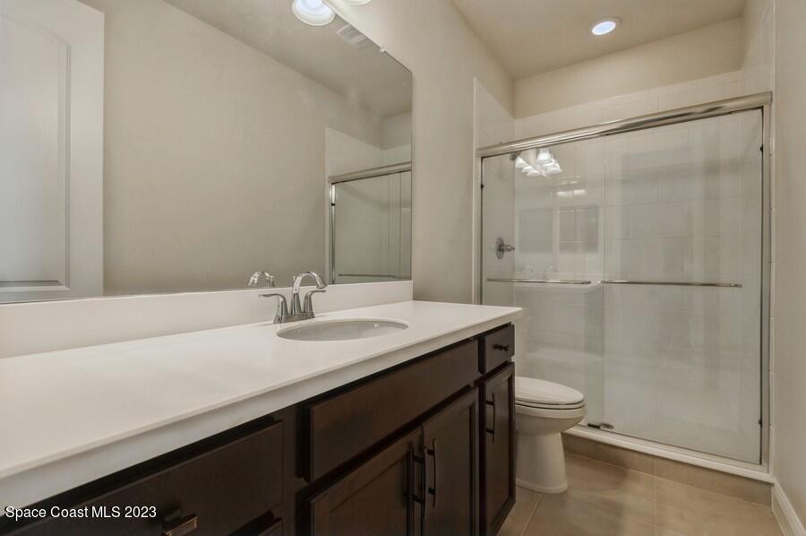 8072 Rungsted Lane Melbourne, FL 32940 - Photo 39 of 59 a bathroom with a granite countertop sink toilet a mirror and shower
