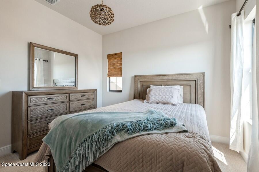 8072 Rungsted Lane Melbourne, FL 32940 - Photo 48 of 59 a bedroom with a bed and a chandelier