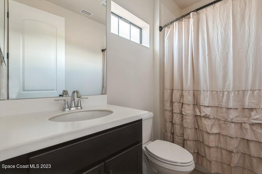8072 Rungsted Lane Melbourne, FL 32940 - Photo 50 of 59 a bathroom with a sink a toilet and shower curtain