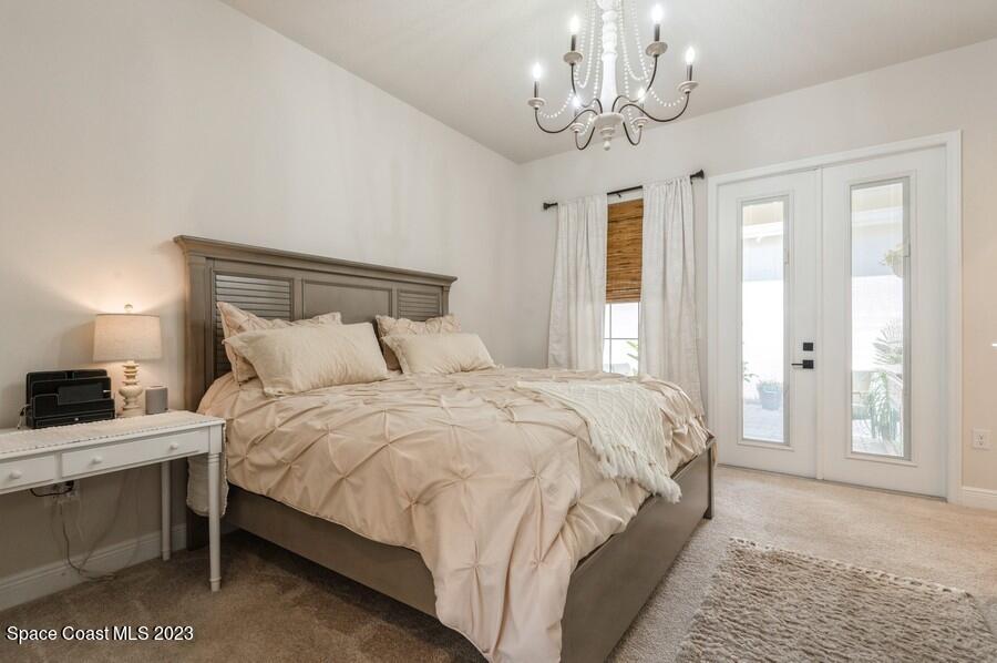 8072 Rungsted Lane Melbourne, FL 32940 - Photo 51 of 59 a bedroom with a large bed and a chandelier