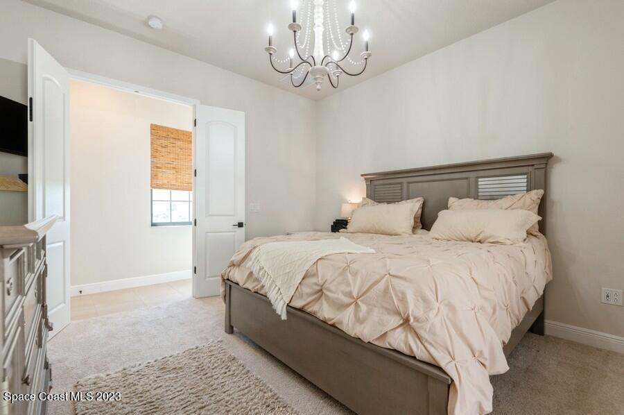 8072 Rungsted Lane Melbourne, FL 32940 - Photo 53 of 59 a bedroom with a bed and a chandelier