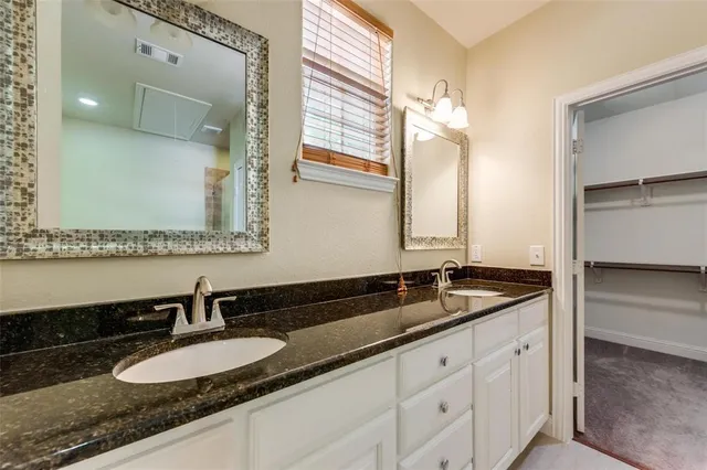 a bathroom with a granite countertop double vanity sink and mirror