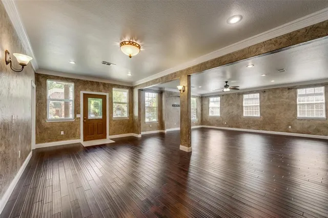 an empty room with wooden floor and windows