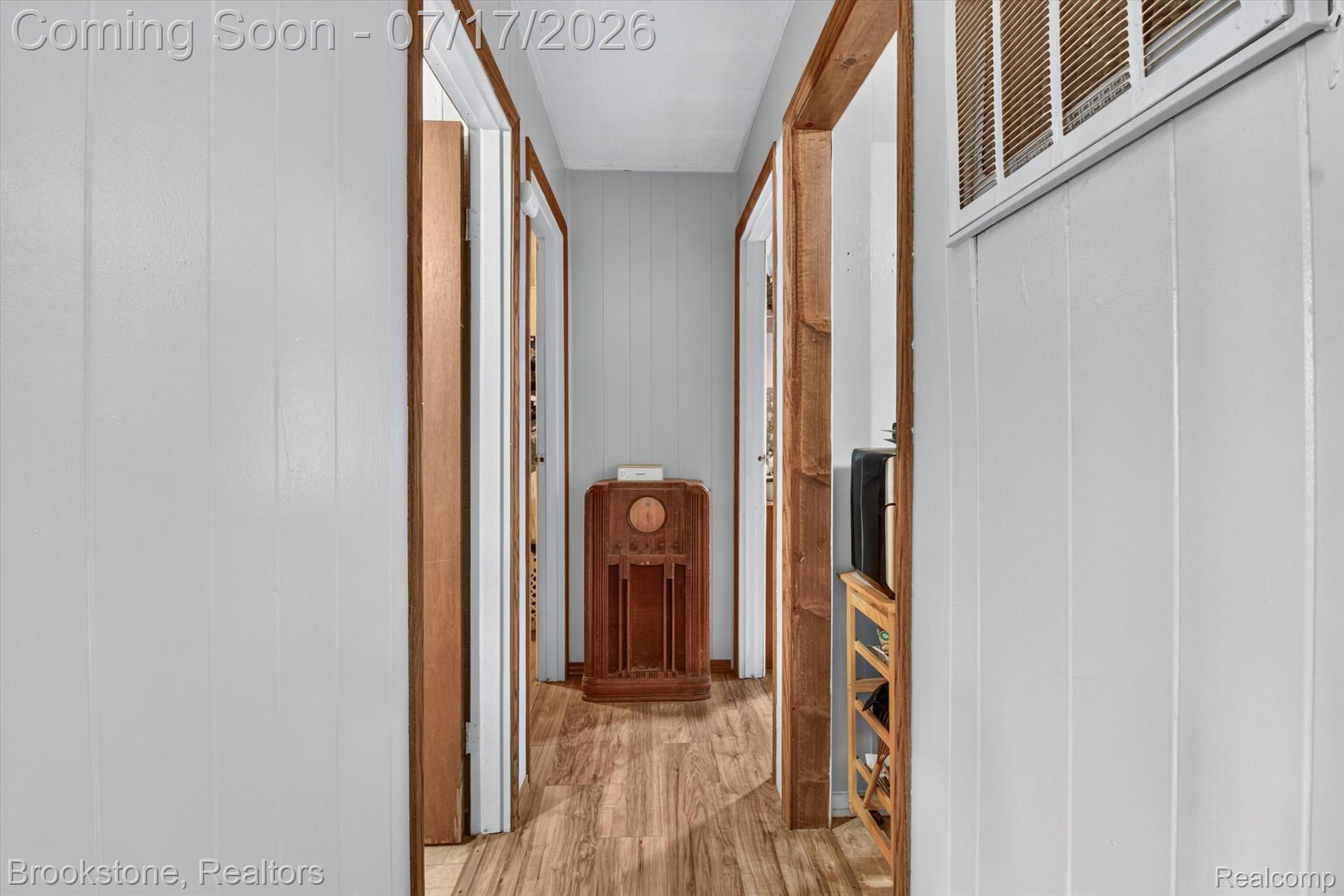 22709 Pleasant Valley Road Hillman, MI 49746 - Photo 16 of 42 Hallway with wood-finish flooring, white vertical plank walls, and natural wood door frames