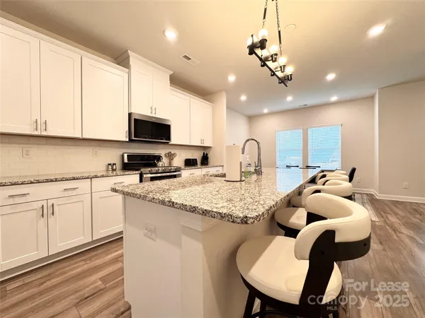 a kitchen with stainless steel appliances granite countertop a sink dishwasher a microwave oven with white cabinets and a granite counter top