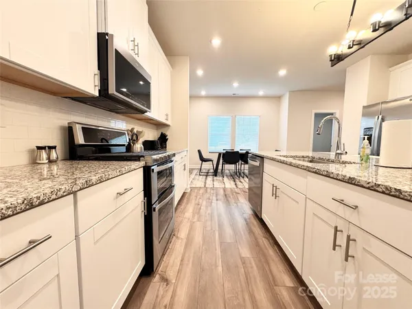 a large kitchen with stainless steel appliances granite countertop a lot of counter space and wooden floors