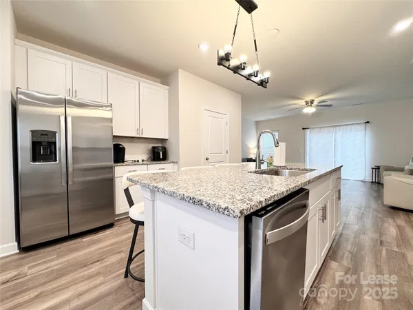 a kitchen with stainless steel appliances granite countertop a kitchen island a stove a refrigerator a oven and a sink with cabinets