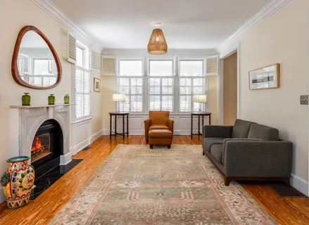 a living room with furniture a rug a fireplace and a window