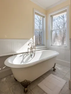 a white bath tub sitting in a bathroom next to a window
