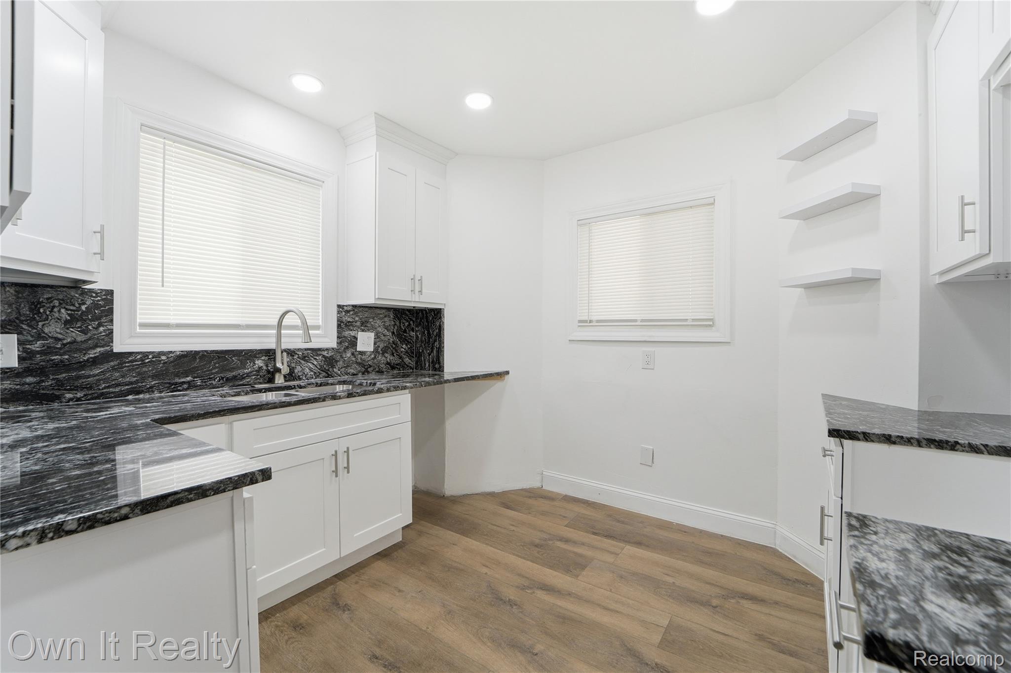 17351 Appoline Street Detroit, MI 48235 - Photo 9 of 34 Kitchen featuring white cabinetry, dark stone countertops and backsplash, a stainless steel sink with a gooseneck faucet, wood-finish flooring, and recessed lighting