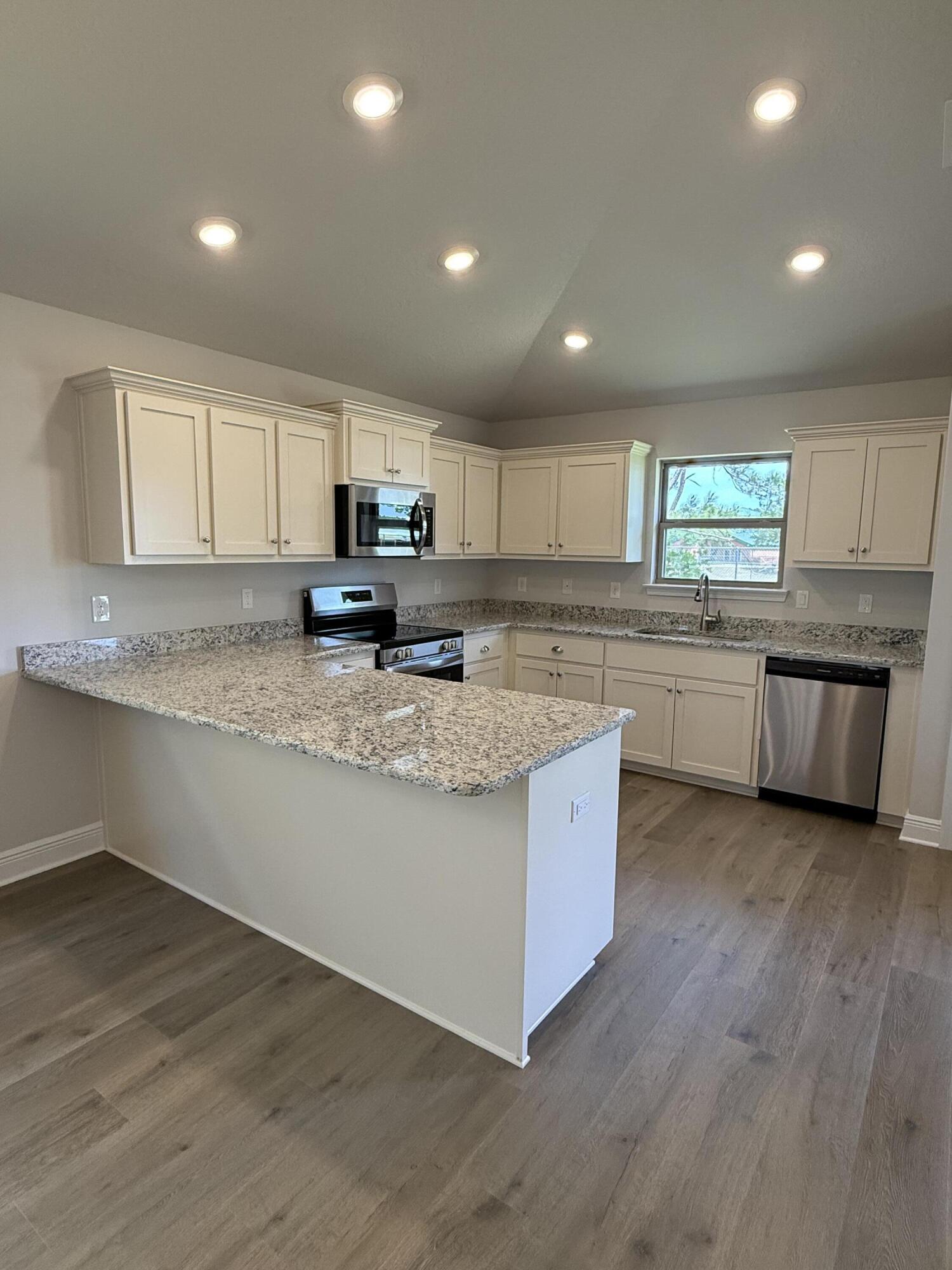 194 Ridgeway Circle Crestview, FL 32536 - Photo 18 of 25 a large kitchen with granite countertop a stove a sink a refrigerator and white cabinets