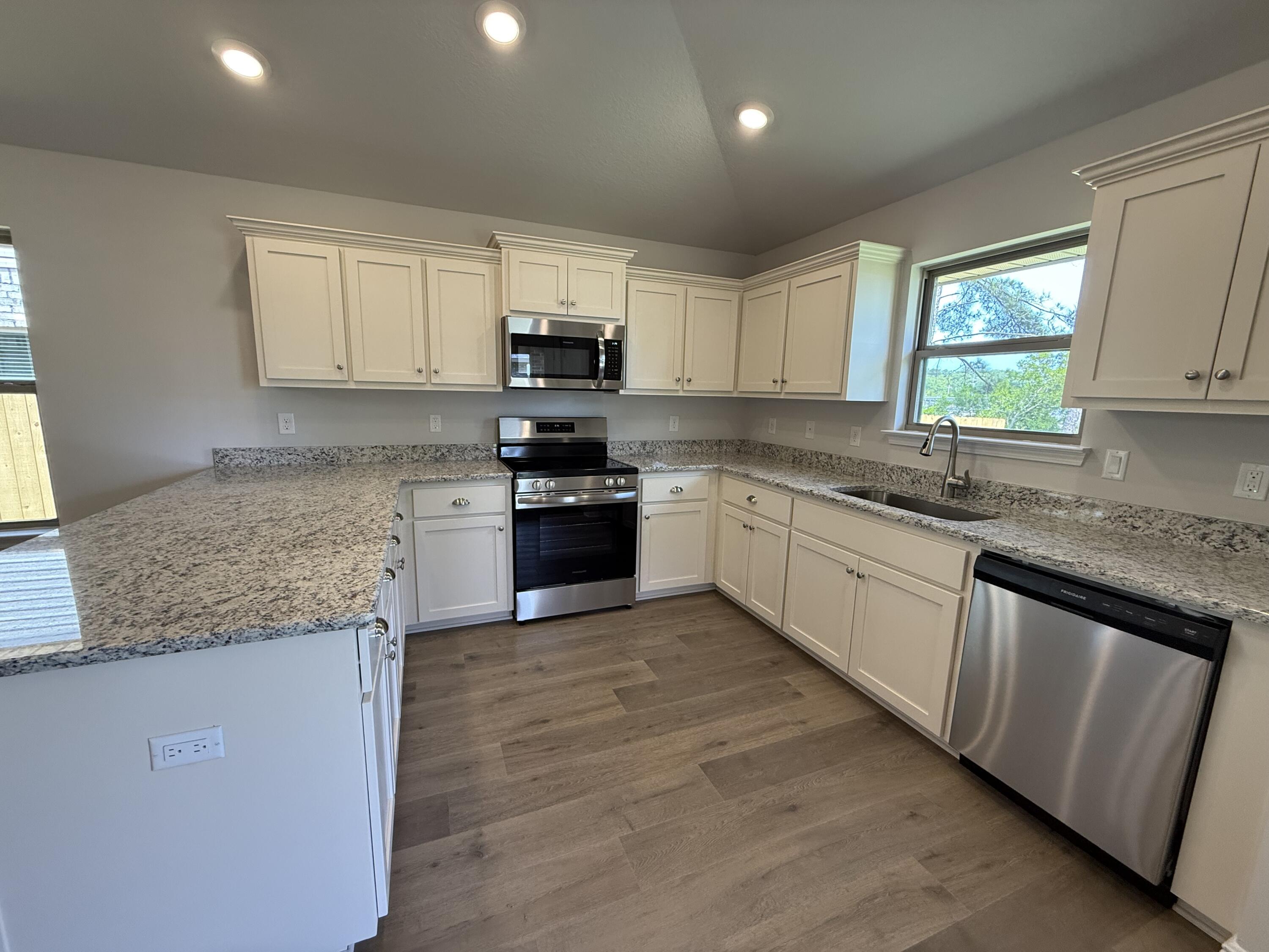 194 Ridgeway Circle Crestview, FL 32536 - Photo 20 of 25 a kitchen with stainless steel appliances granite countertop a sink dishwasher stove and white cabinets with wooden floor