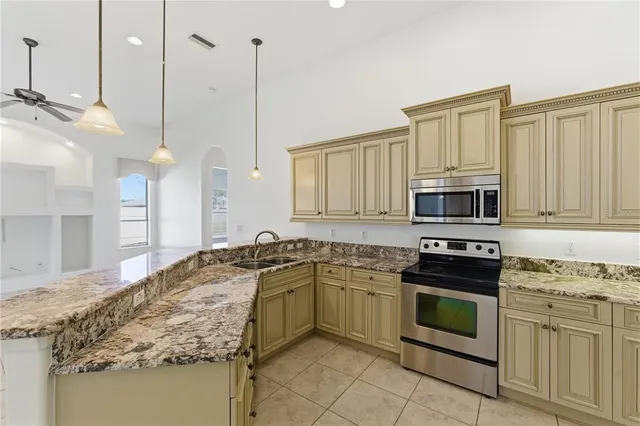 a kitchen with stainless steel appliances granite countertop a sink a stove a oven a refrigerator and island with wooden floor