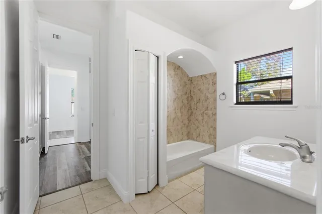 a bathroom with a granite countertop sink a mirror a bathtub and shower