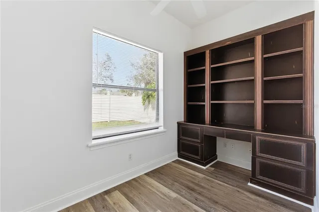 a view of an empty room with a window and wooden floor