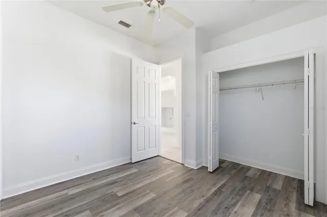 an empty room with wooden floor and a ceiling fan
