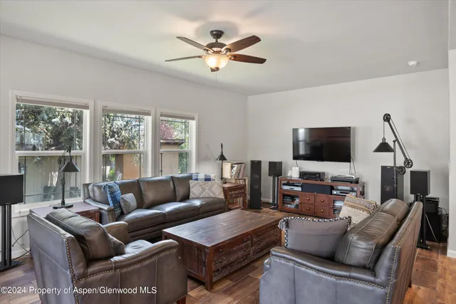 a living room with furniture a ceiling fan and a flat screen tv