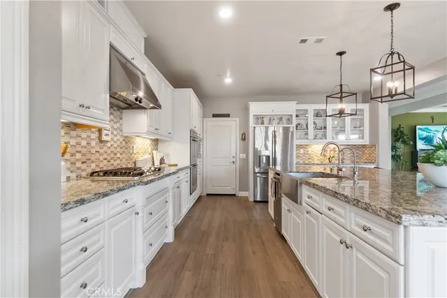 a large kitchen with granite countertop a stove oven and a white cabinets