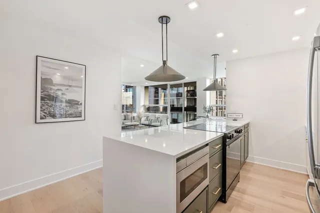 a kitchen with stainless steel appliances granite countertop a sink a stove a dining table and chairs