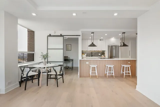 a dining hall with stainless steel appliances kitchen island a table and chairs in it