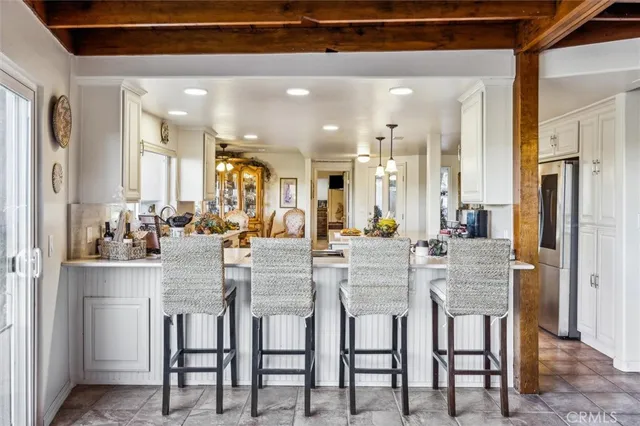 a dining area with stainless steel appliances kitchen island granite countertop a dining table chairs and a refrigerator