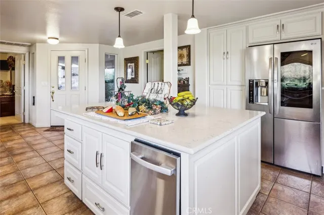 a kitchen that has a lot of white cabinets and stainless steel appliances
