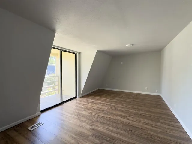 a view of an empty room with wooden floor and stairs