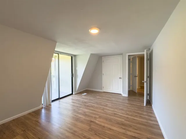 a view of an empty room with wooden floor and closet