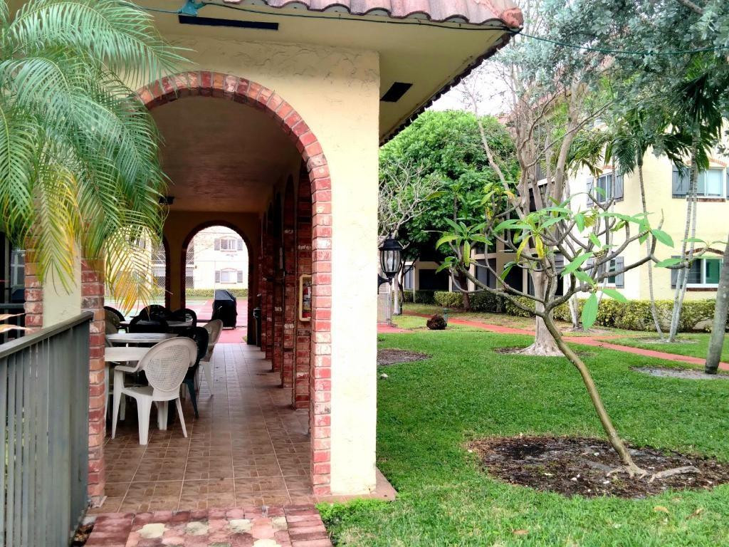 257 South Cypress Road, Unit 423 Pompano Beach, FL 33060 - Photo 29 of 38 a view of a patio with table and chairs potted plants and a palm tree